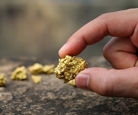 Fingers holding a small ingot of gold