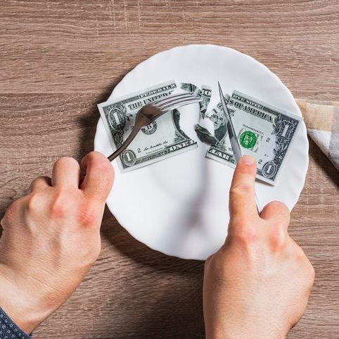 a dollar being cut with a fork and knife on a plate