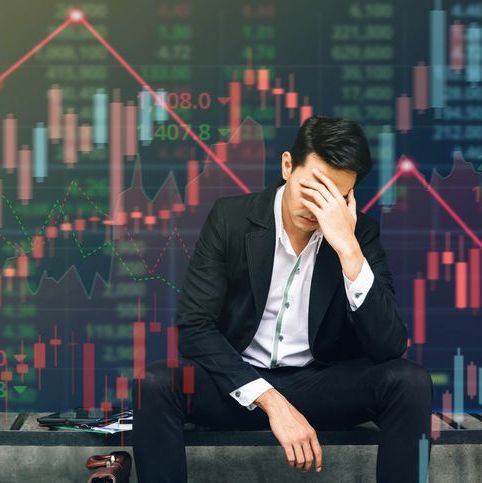 man cover face with volatile charts in background